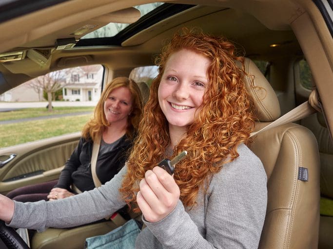 Gill Insurance | Caucasian teenage girl showing key with mother in car