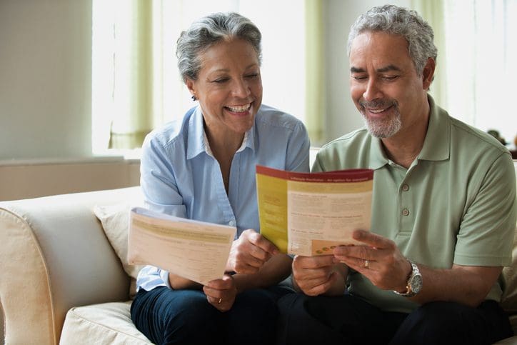 Gill Insurance - Hispanic couple reading pamphlet on sofa