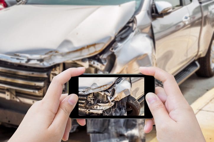 Gill Insurance | woman using mobile smartphone taking photo of car accident damaged for insurance